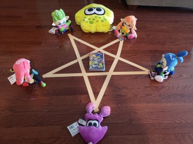 Pentagram summoning circle surrounded by Splatoon plushies, with a copy of Splatoon 3 in the middle