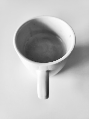 photo en noir et blanc  d'une tasse de café blanche sur une table blanche