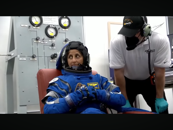 Sunita Williams sitting in a blue flight suit