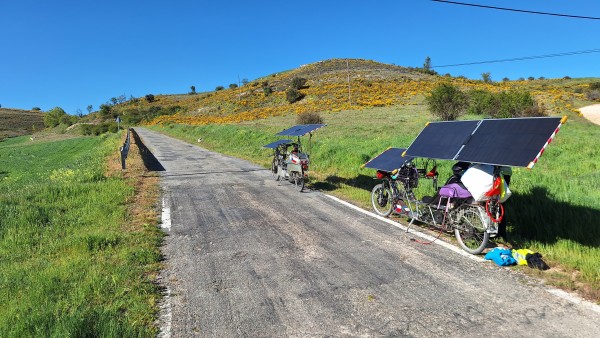 Solar bikes parked by the road. Yellow flowers blooming on the hill.