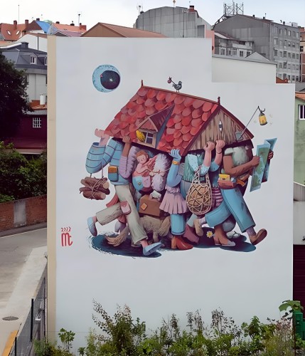 Streetartwall. A charming mural depicting a group of people carrying a house has been sprayed onto the white exterior wall of a multi-storey house in a naive painting style. You can only see their legs as they are all together carrying the red tiled roof of the small house. This is very detailed and lovingly decorated with lots of small details. A small bird is sitting on the roof, one is carrying a map, the other is holding a lamp, suitcases, baskets, a child... a pastel-colored jumble. Above, a blue moon disk illuminates the path that everyone wants to take together. (In the photo there are trees in front of the mural and other houses behind it)
