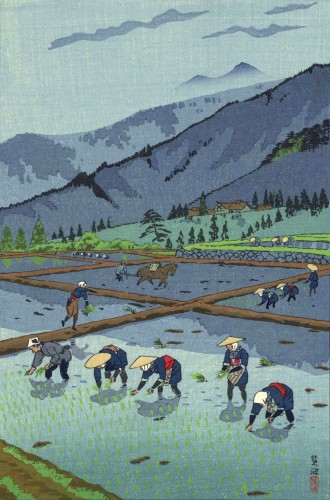 A view of spring rice planting on a mountain farm in Japan. In the foreground, figures in traditional-style clothing and broad bamboo hats or scarves plant rice shoots in a flooded field. The farm consists of a series of squared-off rice fields, each bordered by an earth embankment, and similar figures work in the other sections: planting rice shoots, or in one case, steering a plow behind a horse. Beyond, a large farmhouse and outbuildings stand on top of a hill, surrounded by scattered trees and overlooking the fields; further on, mist clings to the upper reaches of jagged forested mountains. Above, a few tattered clouds cross a blue sky.