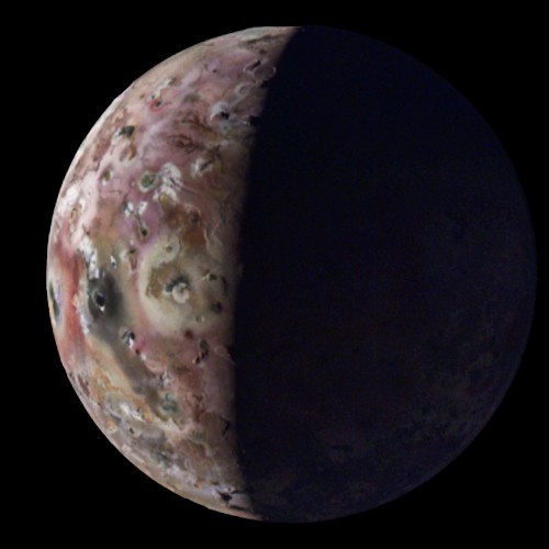 The volcanic moon Io is seen half-lit by the Sun on the left hand side of the image, revealing the moon's south polar region along with unseen mountains and lava lakes.