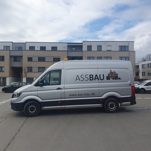 A transporter belonging to a construction company in the middle of the street. The (German) company is called "Ass Bau". 
