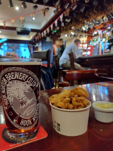 In the Lamplighter pub, St Helier. 

In the foreground is a pint of Old Hooky, a tub of warm pork scratchings & a small pot of apple sauce.

The pub is bedecked in Union Jacks as today is Liberation Day, a public holiday in the Channel Islands, marking the end of its WW2 occupation.