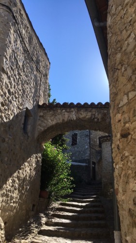 Un escalier à demi ombragé, sous une arcade, dans une ruelle d’un vieux village 