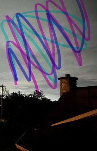 Photo of sky over rooftops. Pink, cyan, and purple highlighter is scribbled in the sky. 