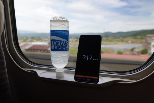 Upside down bottle of Pocari Sweat next to a phone that reads 317 km/h. 