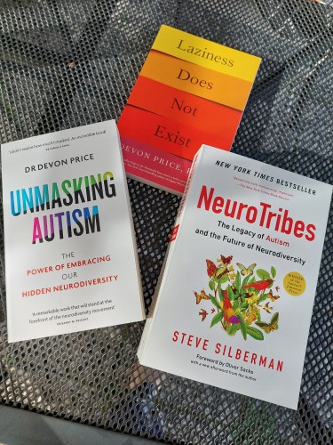 Three books on a table: Unmasking Autism by Devon Price, NeuroTribes by Devon Price, and Laziness Does Not Exist by Devon Price. 