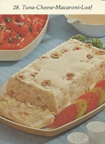 Old recipe card for a tuna cheese macaroni loaf. It’s a rectangular mass of beige. The only bit of color comes from the tomato and parsley garnish.