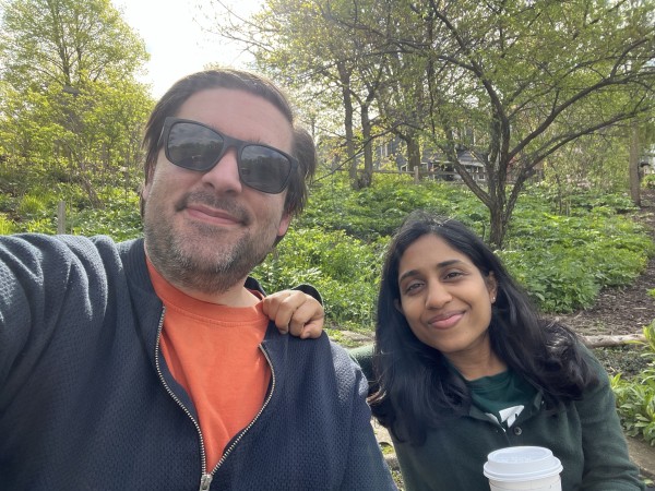 Two people taking a selfie in a park with greenery in the background.