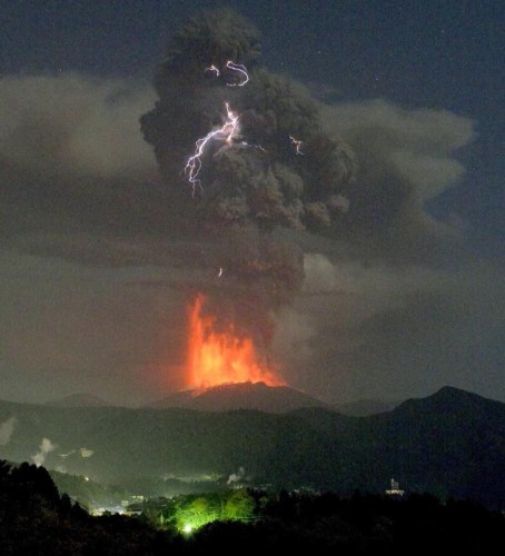 Picture of a volcano erupting, with lightning in the black cloud, and an odd greenish glow in the foreground.