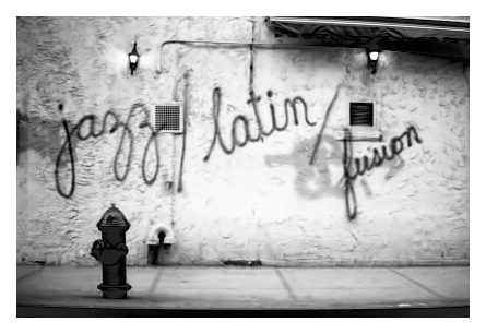 black and white, night. stucco building wall with two widely-spaced lamps and large, spray-painted words, in cursive

jazz / latin / fusion

a sidewalk with hydrant in the foreground.