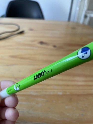 I am holding a pen up diagonally. It is like green with a translucent cap. It says: Lamy ink-x