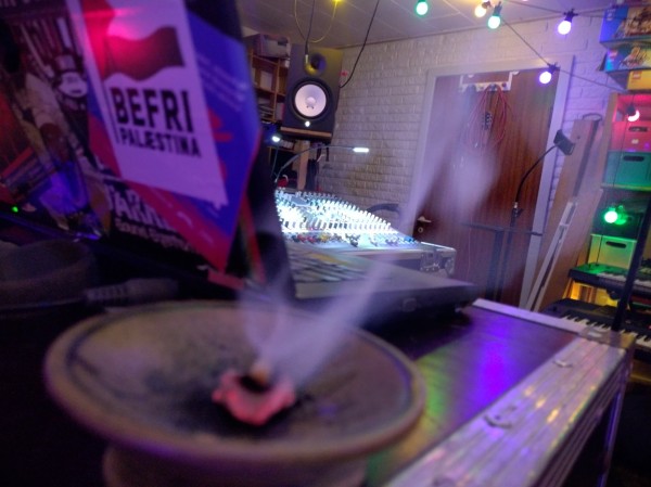 Incense burning on charcoal in front of laptop with free Palestine sticker. Mixing desk is seen in background