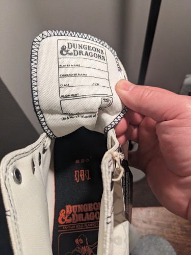 The interior of the tongue of Converse x D&D custom shoes includes the top level data on a D&S character sheet 
Player name
Character name 
Class level 
Hit points 