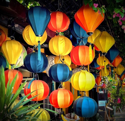 Vibrant and colorful silk lanterns hanging in a cluster. Orange, blue and yellow. 