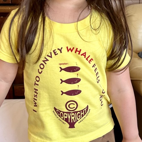 A yellow t-shirt on my 4 year old daughter, with text in an arch that reads “I wish to convey whale feels to you” (with the word“whale” in a different colour) and a sizeable copyright symbol with “copyright” in large letters on a whale’s fluke at the bottom. 