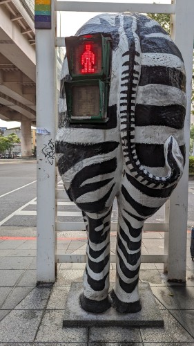 The view from "behind" of a pedestrian crossing signal. The device is embedded "behind" a faux zebra's backside.