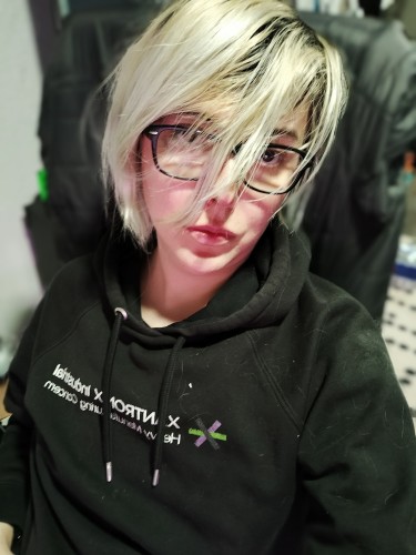 a selfie photograph picture of a blonde twinkoid wearing black rectangle glasses and a XANTRONIX Industrial hoodie. there is fuzz and lint on their hoodie because they cannot be arsed.