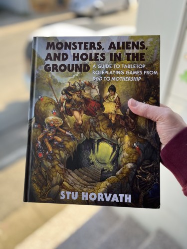 Ich halte ein Buch in die Kamera:
"Monsters, Aliens and Holes in the Ground

A Guide to Tabletop Roleplaying Games from D&D to Mothership

Stu Horvath"