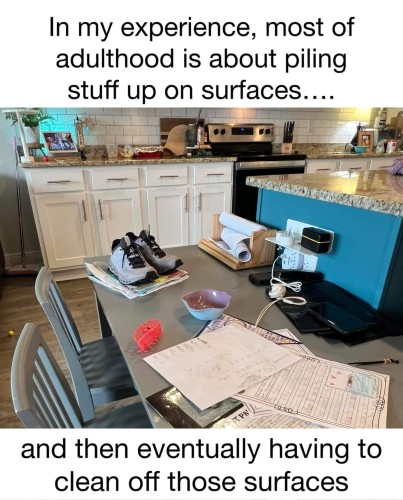 Picture of a cluttered kitchen counter/workstation (papers, athletic shoes, cables, hair clip, etc.) caption reads "In my experience, most of adulthood is about piling stuff up on surfaces… and then eventually having to clean off those surfaces."