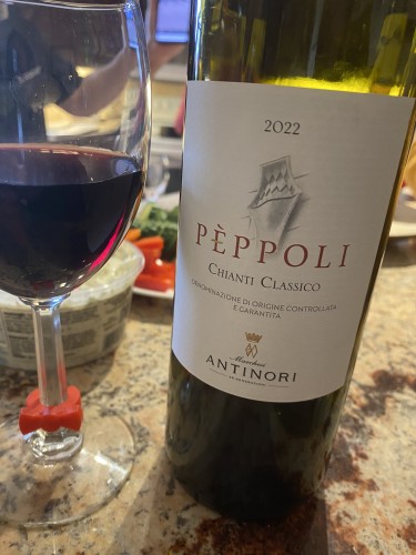 Bottle of Peppoli Chianti Classico next to a glass of it on a marble counter 