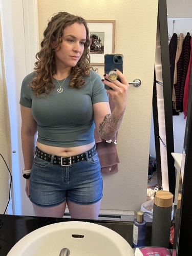 Me, a white woman with curly brown hair. I’m wearing a green top and jean shorts. 