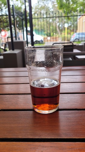 A half drunk pint of beer on an outdoor table at a pub