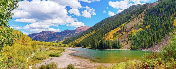 Maroon Bells Panoramic

This is a panoramic image of the Maroon Bells located outside of Aspen Colorado in the Maroon Bells -Snowmass Wilderness.
The foreground of the image is the shoreline of Crater Lake and then the green waters of the lake. 
The left side of the image is framed with an Aspen that is beginning it's seasonal change.
Between the Aspen Tree and the lake on the left you can see the hiking trail as it roughly follows the shore of the lake. 
Between the lake and the Aspen that frames the image is mostly all Aspen trees in the distance in full yellow.
To the right is a steeper terrain that is mostly pine trees with some Aspen trees mixed in.
The sky is partly cloudy with big puffy white clouds.