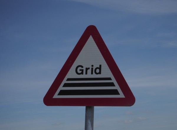 A triangular road sign saying "Grid". There is blue sky behind it.