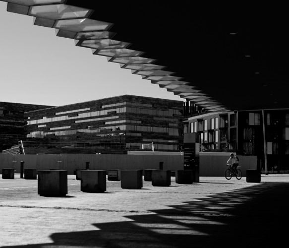 Black and white picture taken in front of Harpa concert hall in Reykjavík. A man on a bike in the distance.