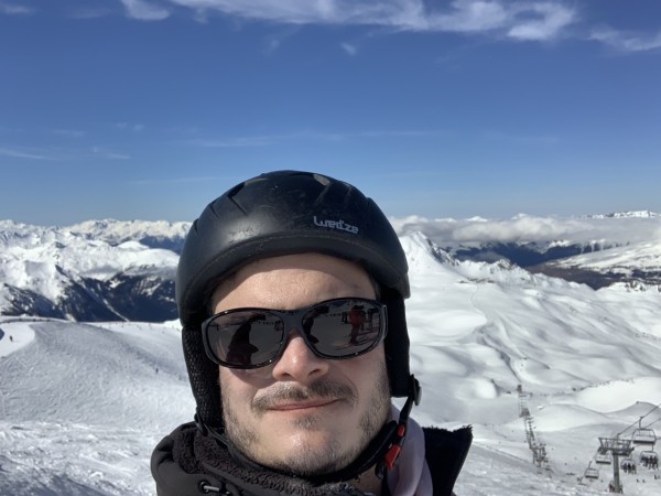 Moi casqué me faisant un selfie avec les montagnes derrière moi. 