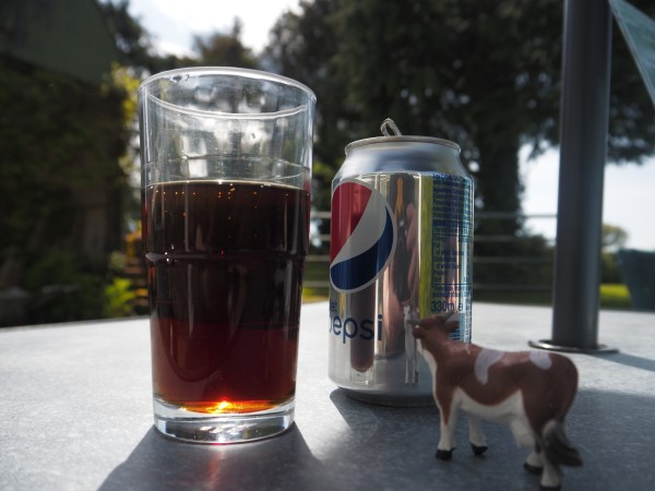 A glass, a can, a small plastic cow. Still the old new Pepsi logo.