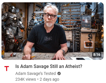 Adam Savage (from Myth Busters fame) sitting at his workbench, facing the camera, with the YouTube caption: "Is Adam Savage Still An Atheist?"