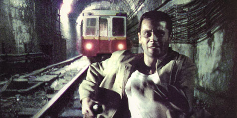 A man running through a tunnel.

Behind him, an underground trin is approaching.