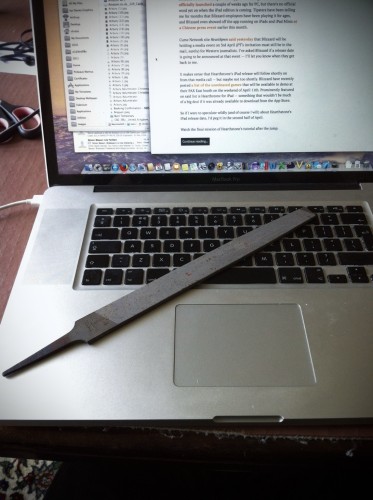 A metal file on a MacBook Pro keyboard, with an article open on the screen.