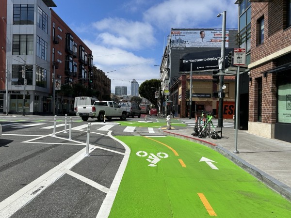 A protected intersection for bikes at Third and Townsend Streets. The Third Street bikeway, in the foreground, is painted green and bidirectional.