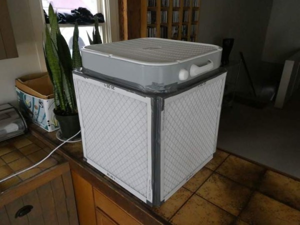 A photograph of a box fan on top of 4 filters arranged to create a cube of purity