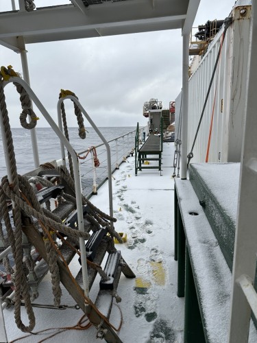 A view along the deck of a ship and everything is covered in snow…