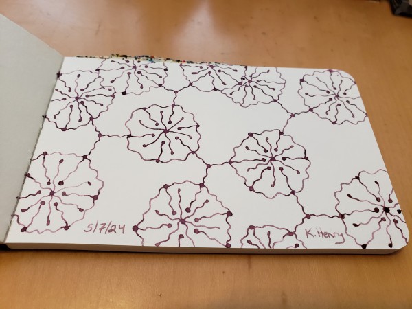 Hand dawn generative art in ink on an open page of my sketchbook. The abstract pattern looks a bit like flowers connected in a network diagram.