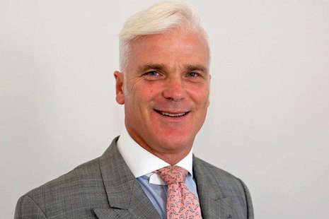 Desmond Swayne, an english politician with funny blond to white hair, he's wearing  blue shirt, grey suit and has an air of bellend about him.

He is also smiling in a weird way.