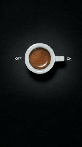cup of espresso from above, in a white cup, on  a black table, with the words off and on -- the handle is pointing to on