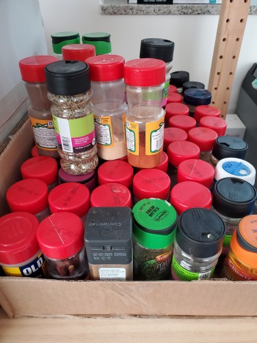 A cardboard container with probably over 60 containers of various spices