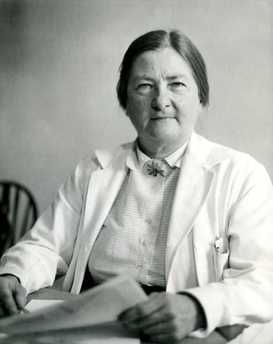 Dorothy Anderson sat behind a desk. She's a white woman with dark hair and is wearing a white doctor's coat.