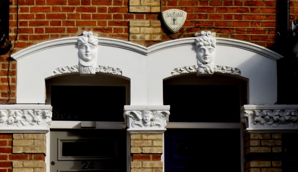 A photograph of two doorways in neighbouring Victorian properties in Islington. The stonework surrounding the doorways is carved, and each door lintel bears a carved face in the middle.

Both these doorways bear apparently female faces. That on the left is rounder with a slight smile, whilst that on the right is leaner and lloks stern.