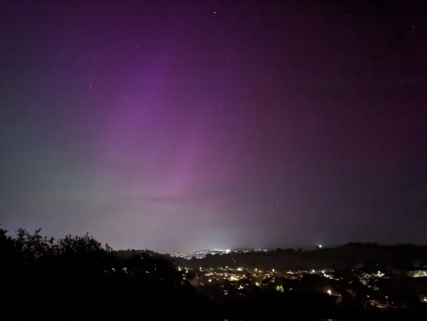 The Aurora Borealis seen facing North-East across Newton Abbot in Devon. The town lights are visible on the ground, the aurora is purplish-red in the centre of the image, greenish towards the bottom-left and absent towards the right of the image, which is more southerly.