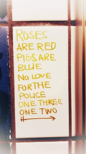 A picture of graffiti on a wall: 
roses are red 
pigs are blue 
no love for the police 
one three one two