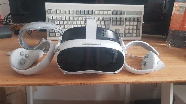Photo d'un casque VR avec ses controlleurs. Le devant du casque réfléchit mes jambes nues