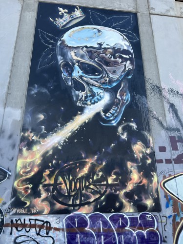 Graffiti art of a fire breathing skull. The skull is chrome.